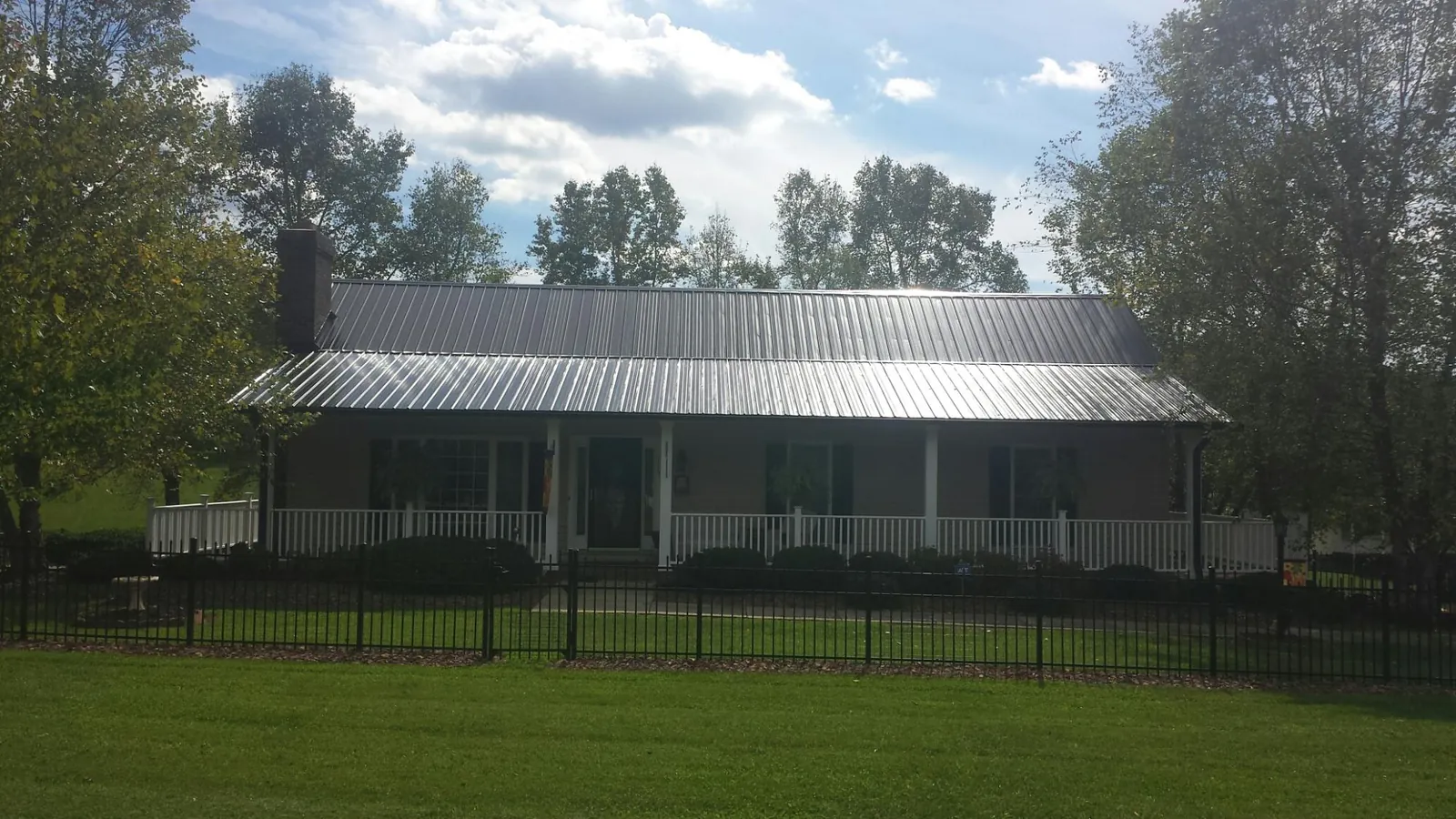 Gray metal roof on a brick ranch with a full width front porch — Gutter Guard Installation work by our crew in Galt