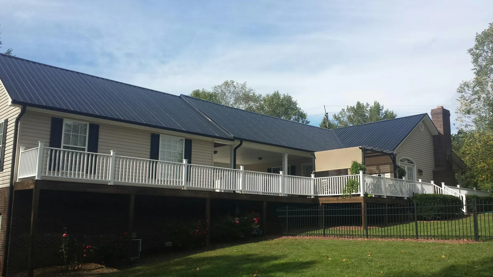 Black metal roof above a long white railed deck on a hillside home in Galt
