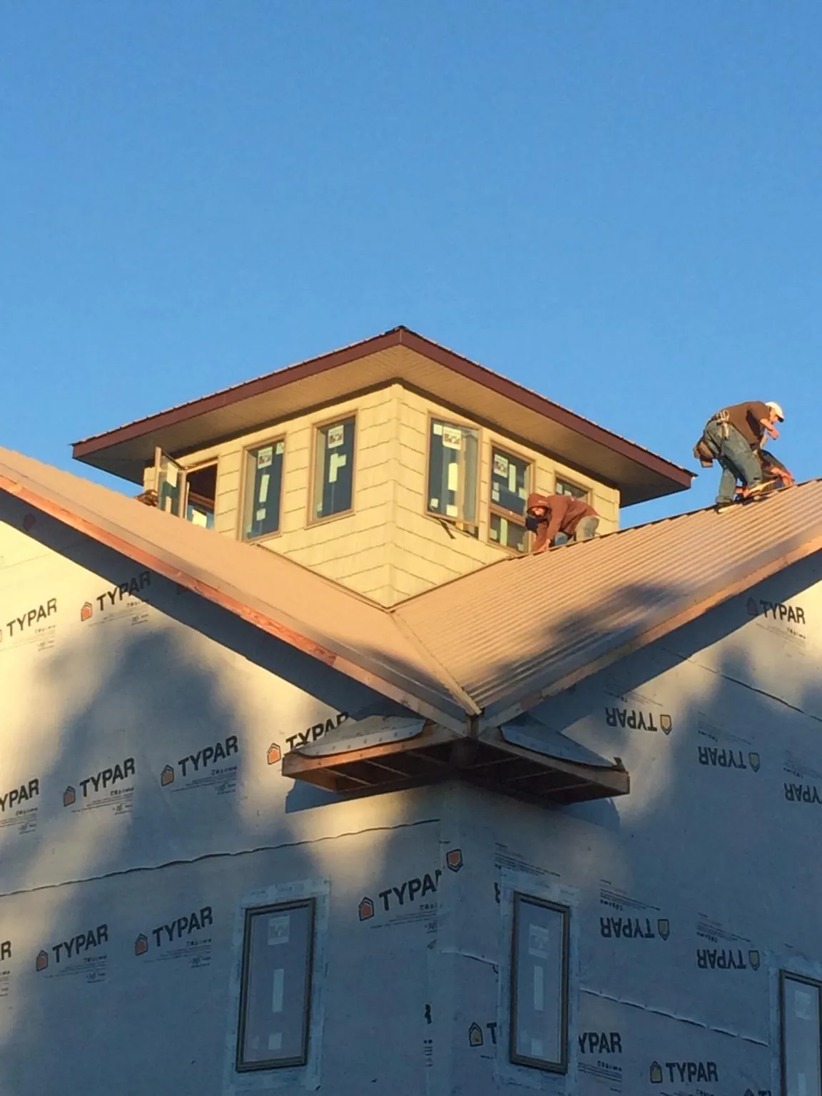 Roofers working around a rooftop cupola on a new metal roof at sunset — Roof Waterproofing in Galt by Roofing Brothers
